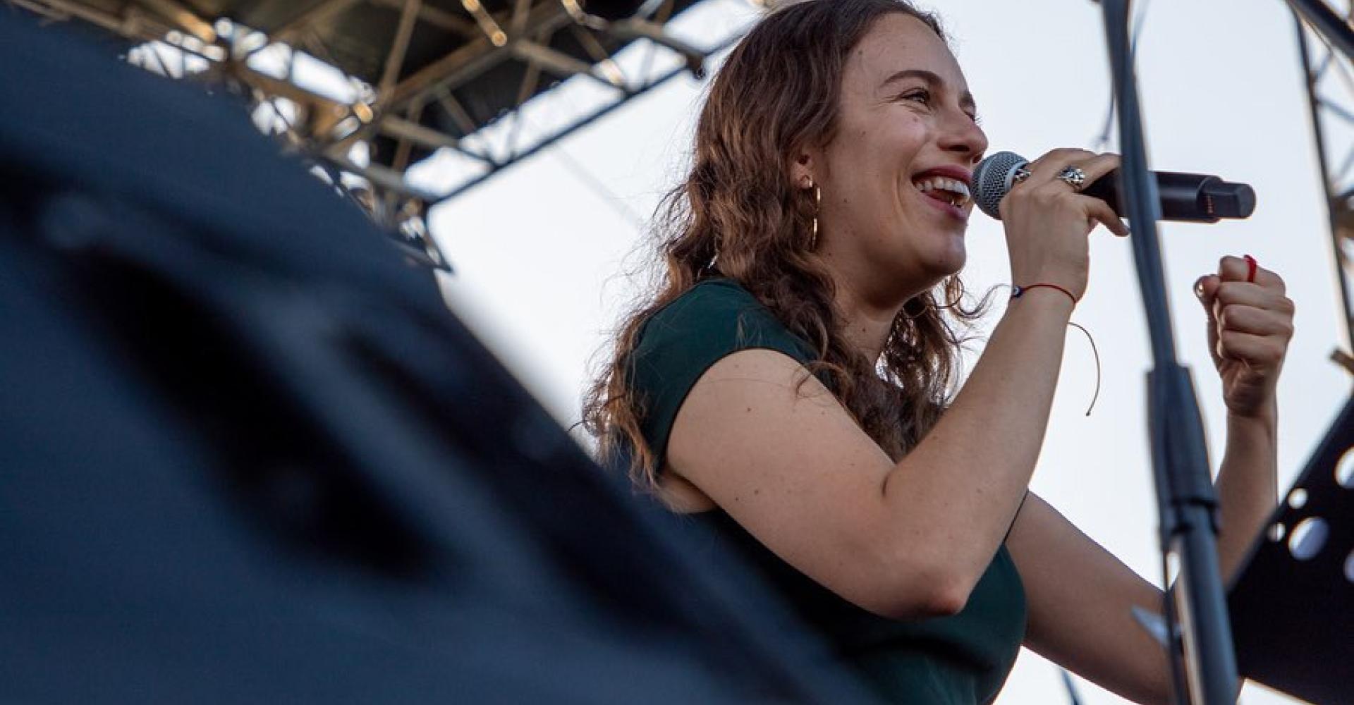 Delfina Cheb holds a microphone and smiles from the outdoor stage during the Panama Jazz Festival.
